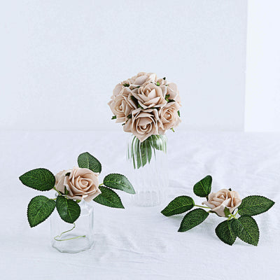 Artificial cream roses in glass vases with green leaves.
