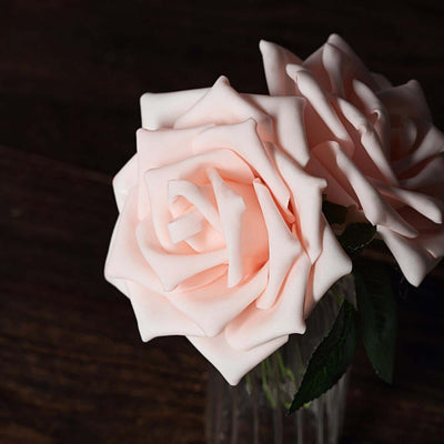 Pink artificial roses in a clear vase on a wooden surface.
