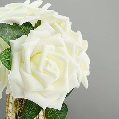 White rose bouquet with green leaves in a decorative vase.