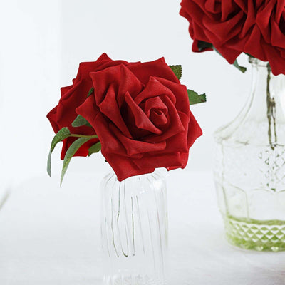 Red artificial roses in a clear vase on a white background.