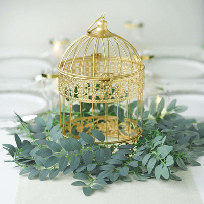 Gold decorative birdcage centerpiece with greenery on a table setting.