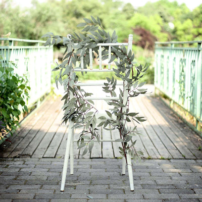 White chair adorned with greenery on a wooden deck.