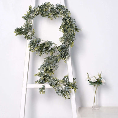 Eucalyptus wreath displayed on a ladder against a white backdrop