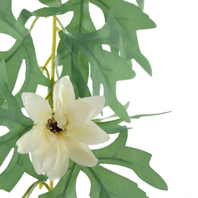 Artificial white flower with green leaves on a plain background