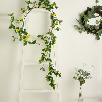 Floral garland with yellow flowers on a white ladder and greenery decor.