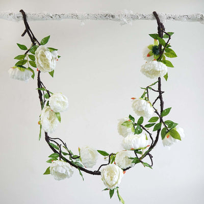 White floral garland with green leaves hanging on a branch