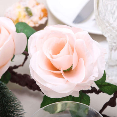 Pink silk rose flower with green leaves on a dining table setting.