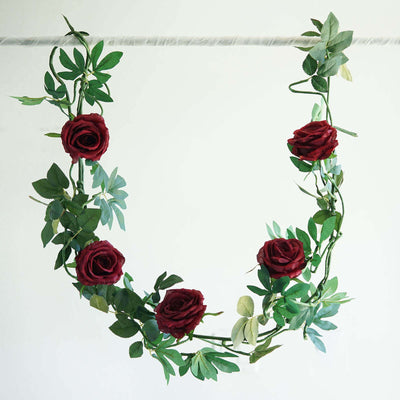 Artificial rose garland with green leaves on a white background