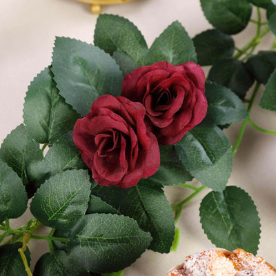Red artificial roses with green leaves on a soft background.