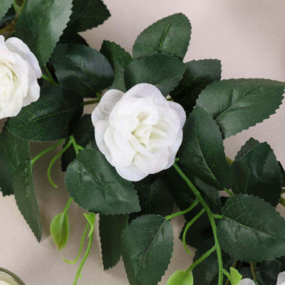 Artificial white rose with green leaves on a neutral background.