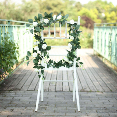 White chair adorned with greenery and white flowers on a wooden path.