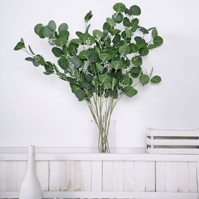 Eucalyptus branches in a glass vase on a white shelf