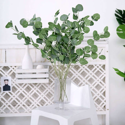 Eucalyptus bouquet in a clear vase on a minimalist white chair.