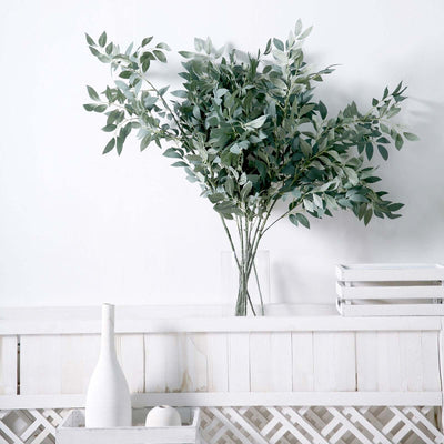 Artificial eucalyptus plant arrangement in a clear vase.