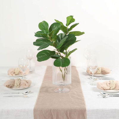 Fiddle leaf fig in a clear vase on a dining table with elegant settings