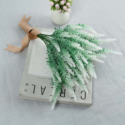 Artificial green and white flower bouquet on a book with a ribbon.