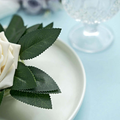 White plate with faux rose and leaves, elegant table setting.