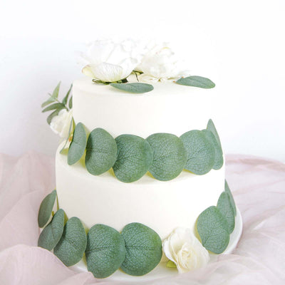 Elegant two-tier cake adorned with fresh eucalyptus and white roses.