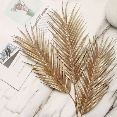 Gold palm leaves arrangement on marble surface.