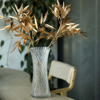 Elegant clear glass vase with golden leaves arrangement.