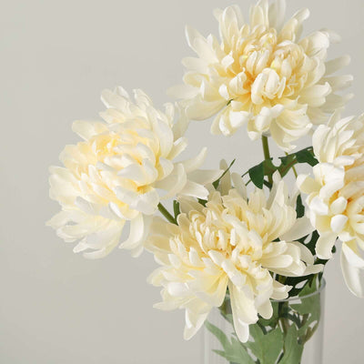 Cream faux flowers in a clear vase, showcasing a delicate arrangement.