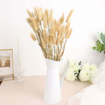 White vase filled with dried flowers on a light surface