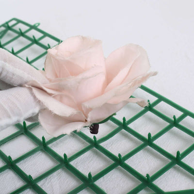 Pink fabric flower on green crafting grid.