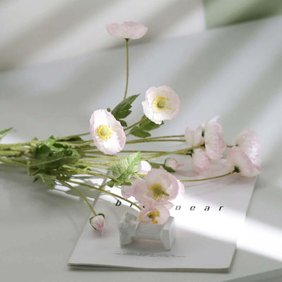 Decorative pink flowers beside a small ceramic figurine on a magazine.