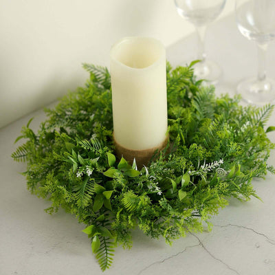 Greenery candle centerpiece with a white pillar candle and decorative foliage.