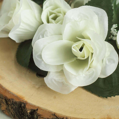 Artificial white rose flowers on a wooden surface.