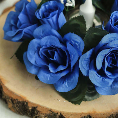 Blue silk roses with green leaves on a wooden slice base.