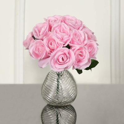 Pink artificial roses in a clear glass vase.