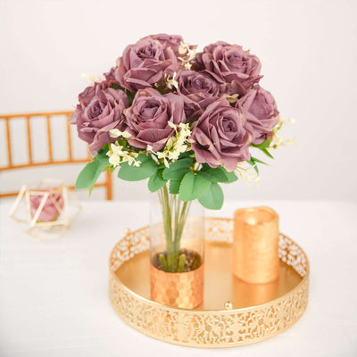 Purple rose bouquet in a gold vase on a decorative tray.