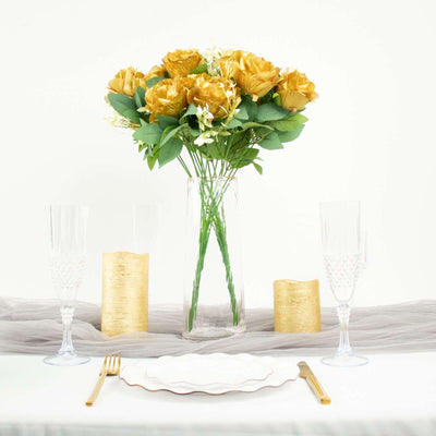 Gold rose bouquet in a clear vase on a table setting with elegant decor.