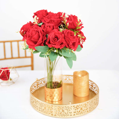 Red roses in a gold vase on a decorative tray.