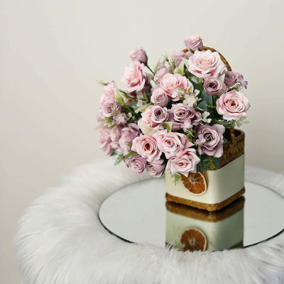 Pink rose bouquet in a decorative basket on a mirrored table.