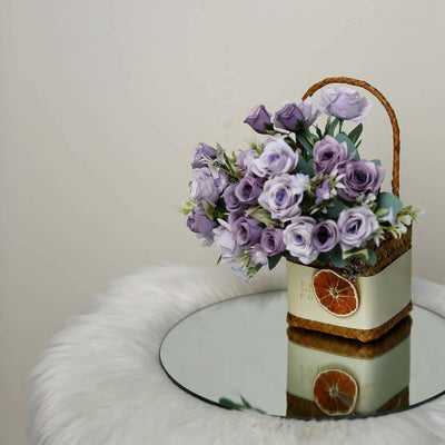 Purple rose bouquet in a decorative basket on a mirrored table.