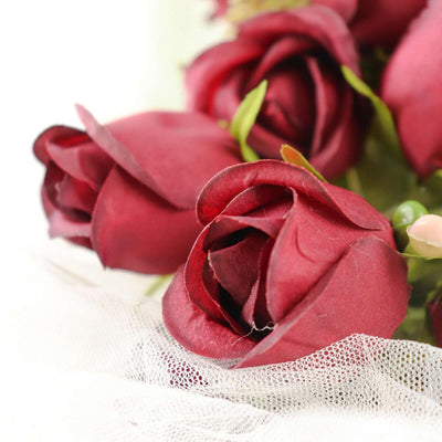 Red silk roses on a delicate fabric background.