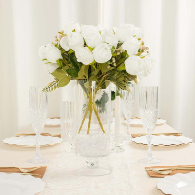 Elegant white rose bouquet in a clear vase on a beautifully set dining table.