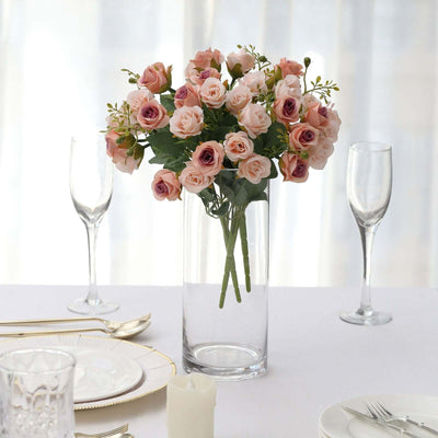 Elegant faux rose bouquet in a clear vase on a dining table.