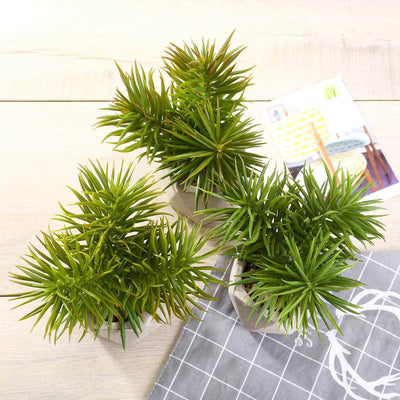 Three vibrant faux succulents in modern pots on a wooden surface.