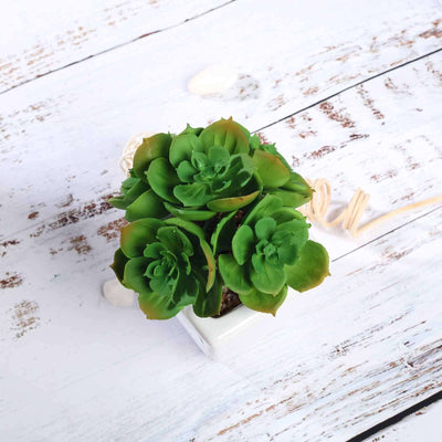 Artificial succulent plant in a white pot on a rustic wood surface.