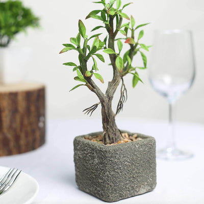 Artificial potted tree in a textured grey planter.