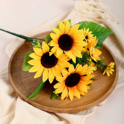Bouquet of vibrant artificial sunflowers on a wooden plate.