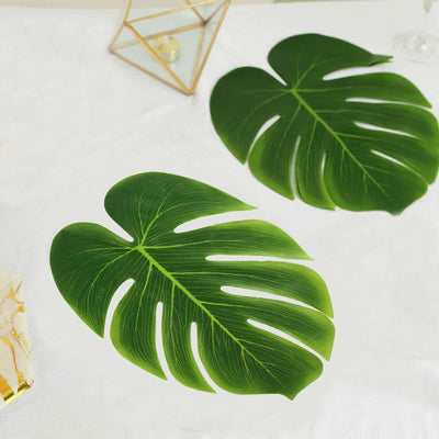 Two vibrant green monstera leaves on a white surface.