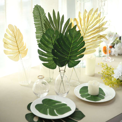 Decorative tropical leaves in vases on a table setting with plates and candles.