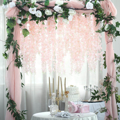 Floral wedding arch with pink flowers and greenery, elegantly styled for events.