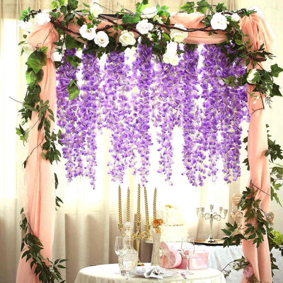 Purple wisteria flower arch with white roses and soft draping fabric.