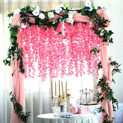 Pink floral wedding backdrop with draped fabric and greenery.
