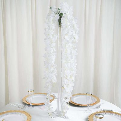 Elegant white orchid centerpiece in tall glass vase for table decor.